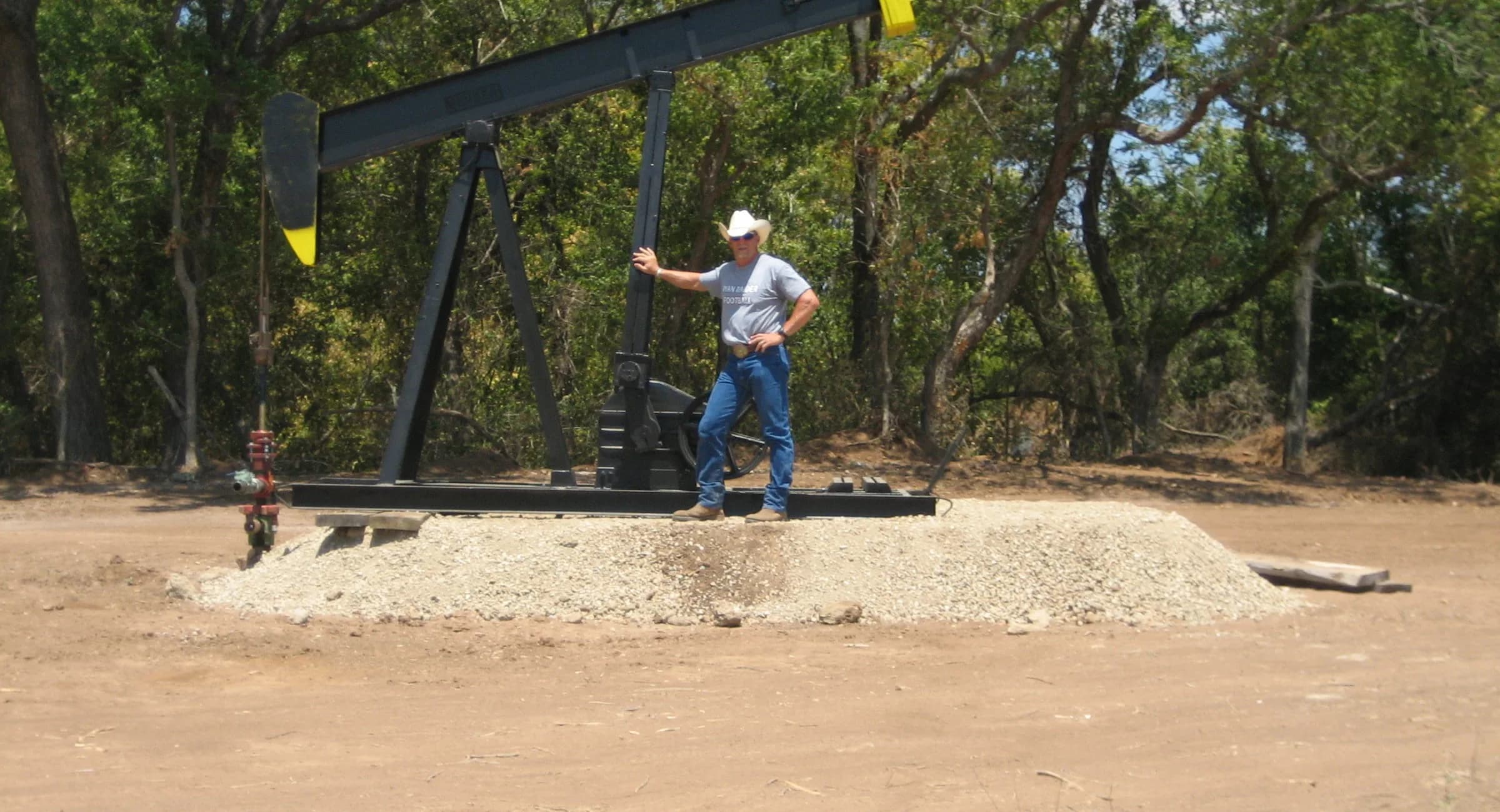 Jeff Schuckers standing beside a pumpjack on a wooded lease site